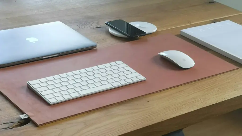 Brown leather desk pad with keyboard, mouse, and laptop