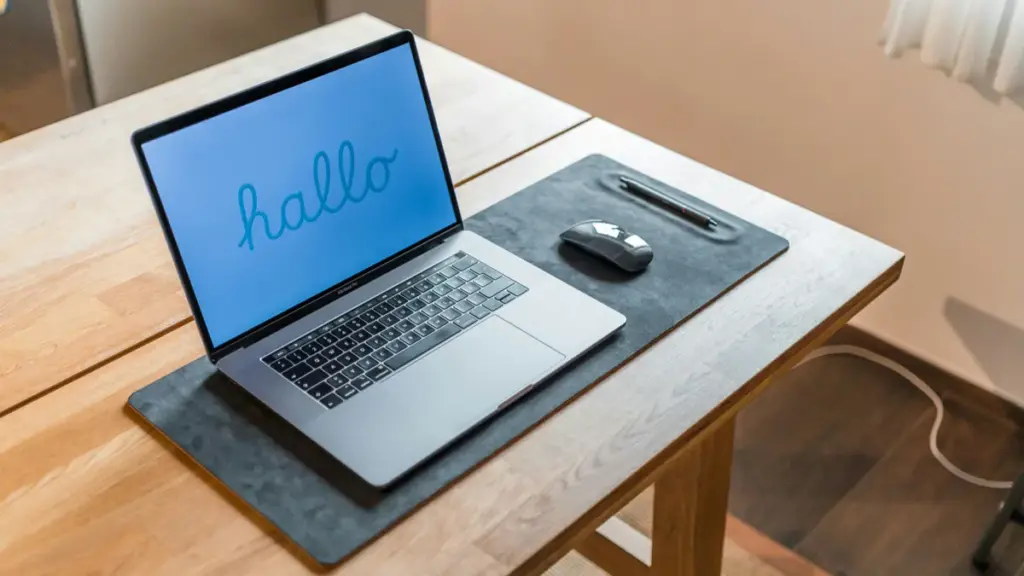 Open laptop and mouse placed on a black desk mat
