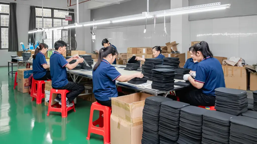 Workers assembling and packaging mouse pads in factory assembly line