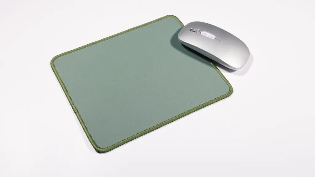 Sage green fabric mousepad and silver wireless mouse on white background