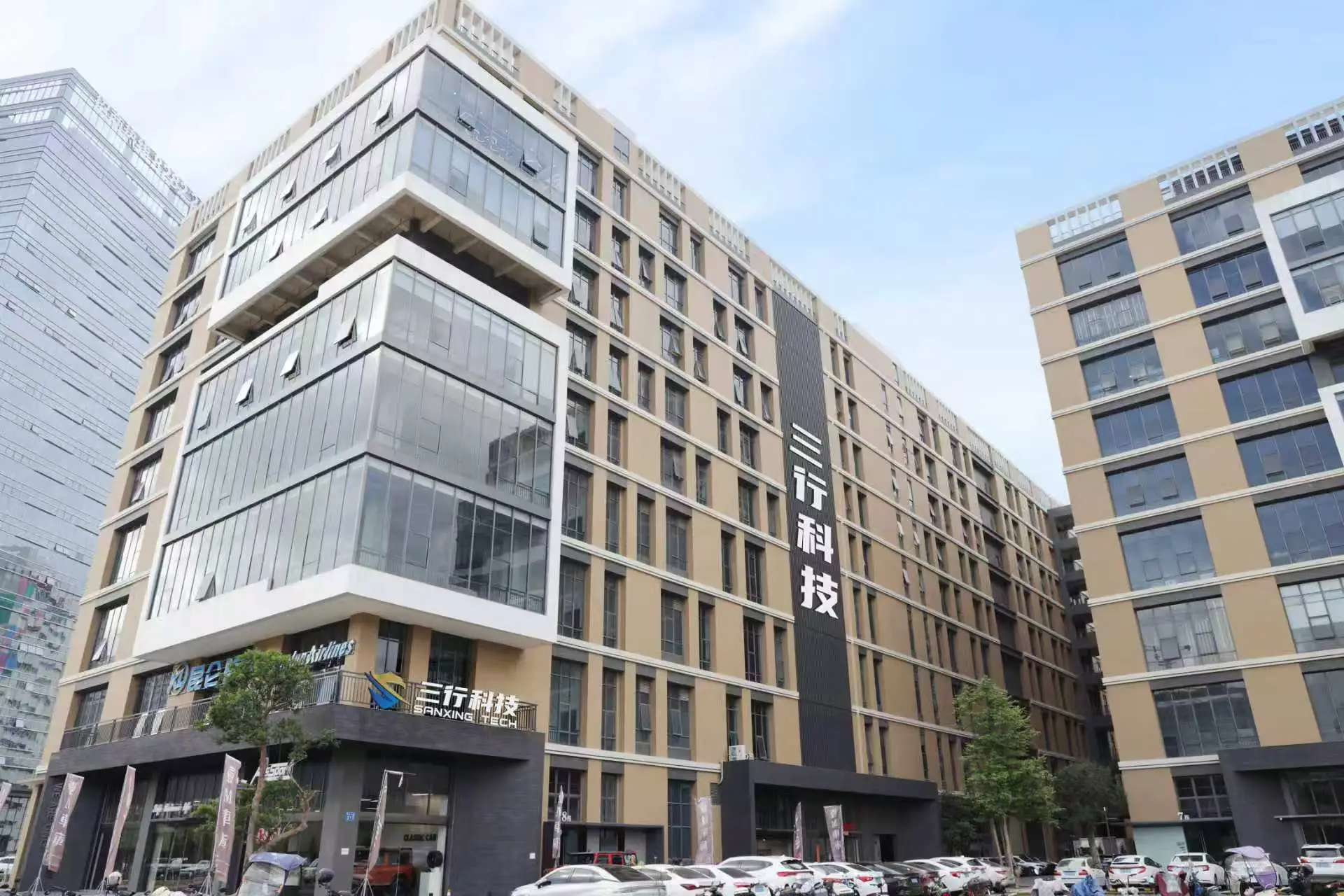 Modern beige office building with Sanxing Tech signage and parking lot